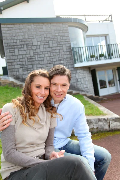 Couple sitting in front of their new home — Stock Photo, Image
