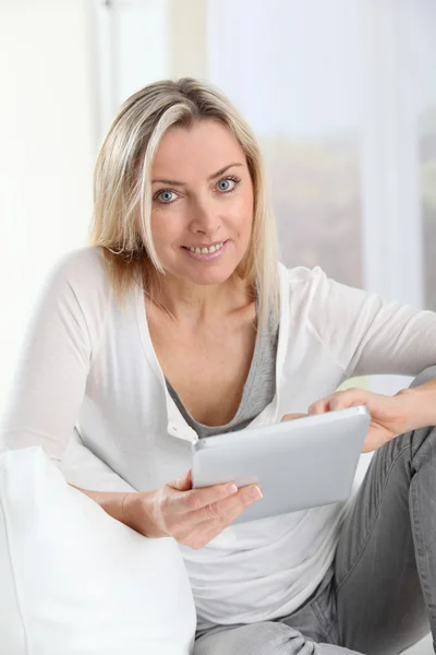 Blond kobieta w domu za pomocą elektronicznego tabletki — Zdjęcie stockowe