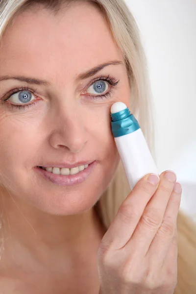 Blonde vrouw toepassing anti-veroudert serum op haar huid — Stockfoto