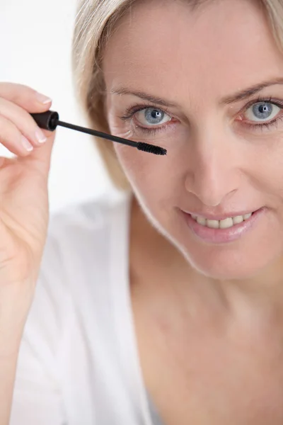 Mulher loira bonita aplicando maquiagem em seu rosto — Fotografia de Stock