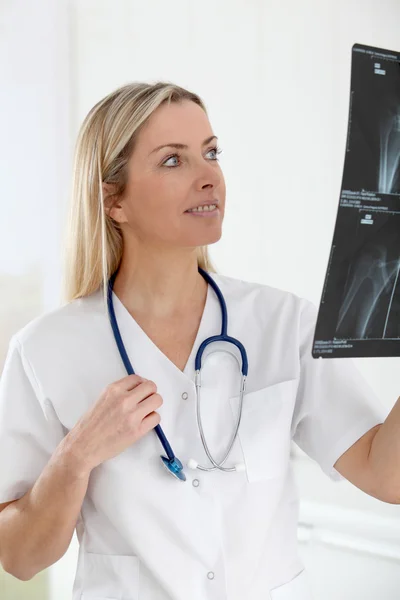 Beautiful blond nurse looking at X-ray — Stock Photo, Image