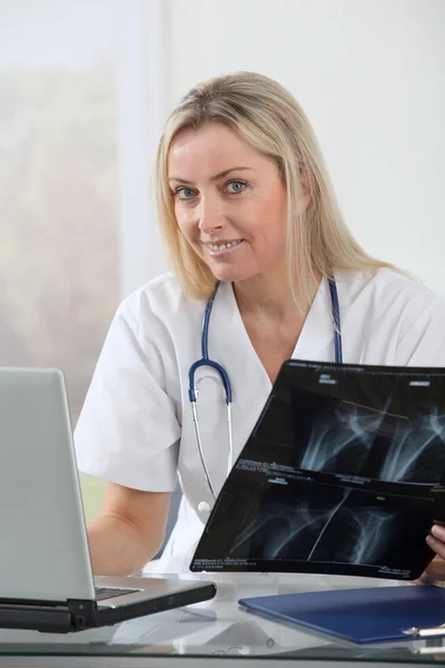 Vacker blond sjuksköterska tittar på röntgen — Stockfoto