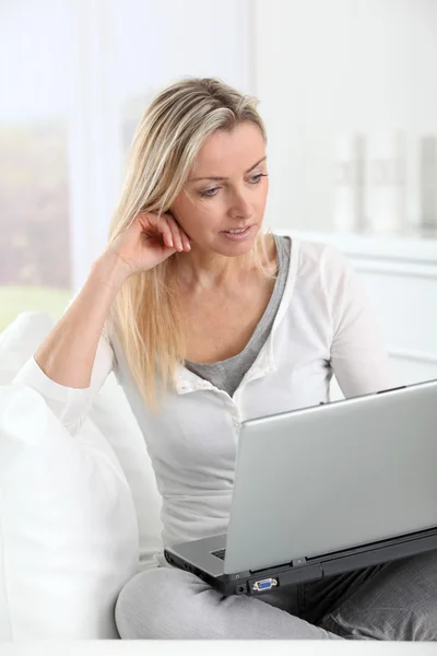Erwachsene blonde Frau im Internet zu Hause verbunden Stockbild