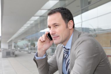 Salesman talking on the phone outside congress center clipart