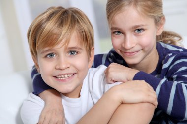 Portrait of young children sitting in sofa at home clipart