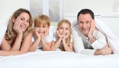 Parents and children laying in bed in the morning clipart