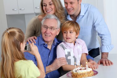 Little girl taking picture of family on birthday celebration clipart