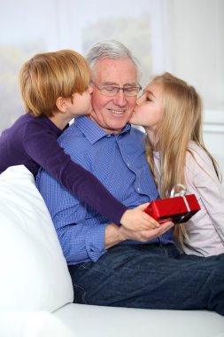 Kids giving birthday gift to their grandfather clipart