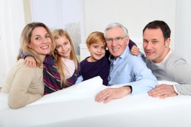 Portrait of happy family sitting in sofa at home clipart