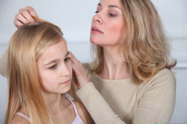 Mother treating daughter's hair against lice clipart
