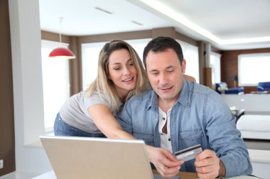 Couple doing online shopping wih laptop computer clipart