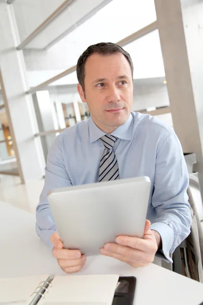 Affärsman som sitter på kontoret med elektroniska tab — Stockfoto