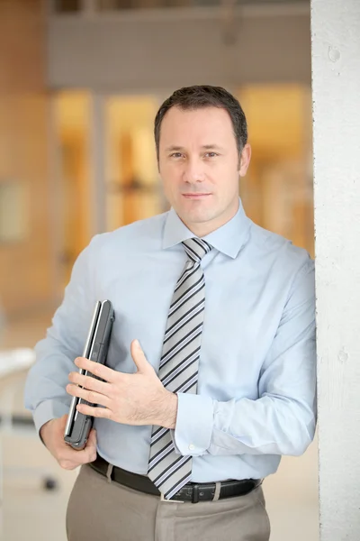 Бизнесмен, стоящий в холле с ноутбуком — стоковое фото