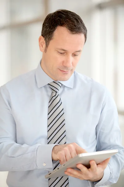 Geschäftsmann steht in Halle mit elektronischer Registerkarte — Stockfoto