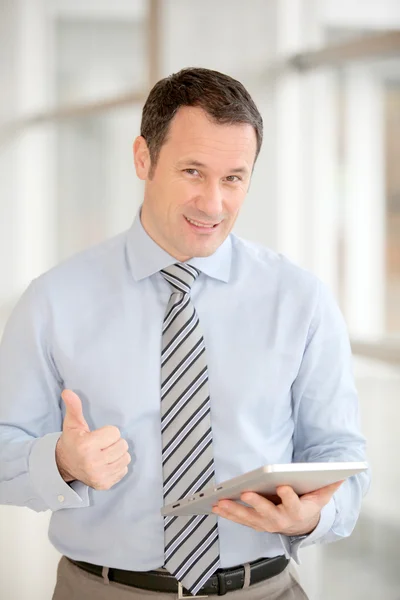 Geschäftsmann steht in Halle mit elektronischer Registerkarte — Stockfoto