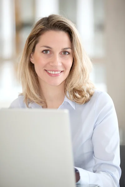 Dizüstü bilgisayar önünde gülümseyen ofis çalışanı — Stok fotoğraf