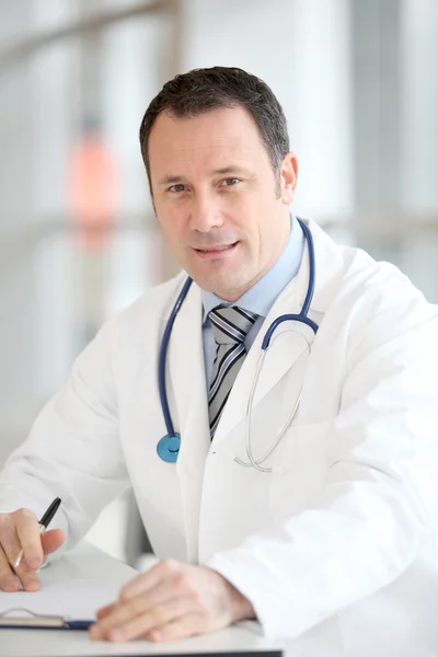 Zbliżenie przystojny lekarz siedzi przy biurku — Zdjęcie stockowe