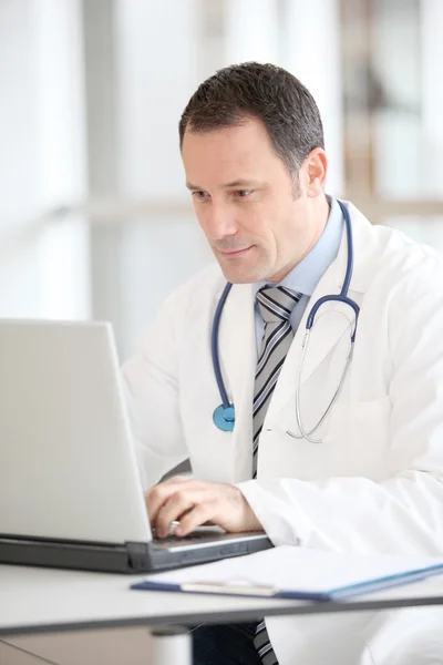 Arzt sitzt mit Laptop am Schreibtisch — Stockfoto