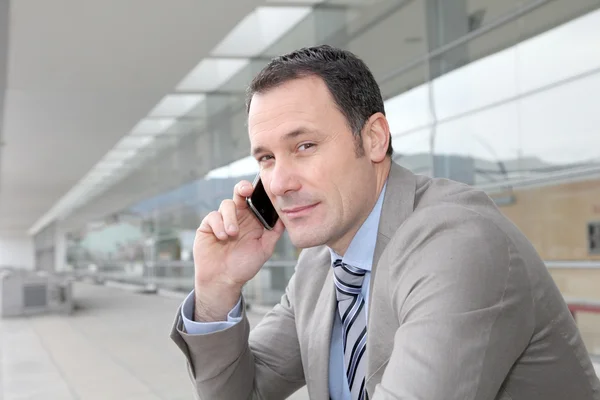 Salesman talking on the phone outside congress center — Stock Photo, Image
