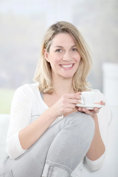 Donna bionda in divano con in mano una tazza di caffè — Foto Stock
