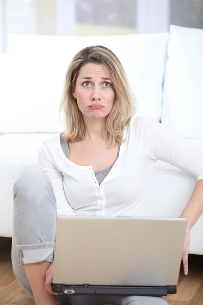 Kadın üzgün bakışla dizüstü bilgisayar kullanarak — Stok fotoğraf