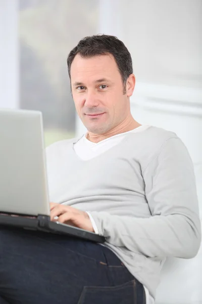 Dizüstü bilgisayar kullanan koltukta oturan adam — Stok fotoğraf