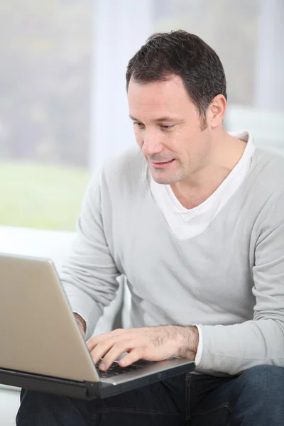 Man sitting in couch using laptop computer — Stock Photo, Image