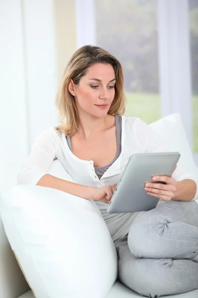 Kobieta za pomocą elektronicznej karty siedzi w kanapie — Zdjęcie stockowe