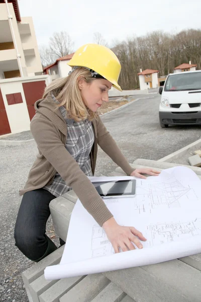 Engenheira mulher olhando para o plano no canteiro de obras — Fotografia de Stock