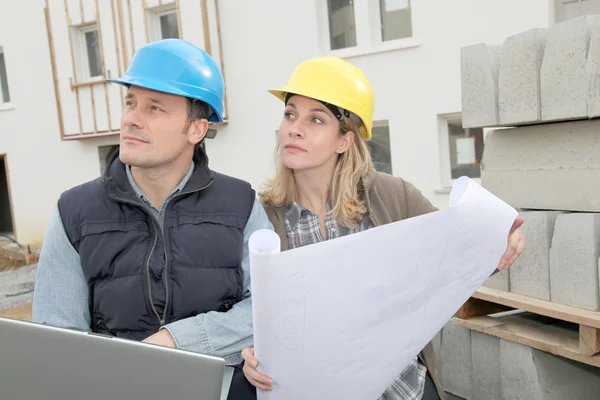 Arquitecto e ingeniero mirando el plan en el sitio de construcción — Foto de Stock