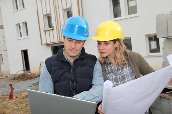 Arquitecto e ingeniero mirando el plan en el sitio de construcción — Foto de Stock