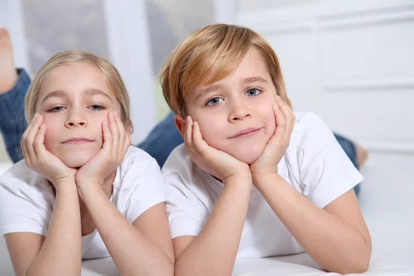 Blonďatá děti v sofa s rukou na bradě — Stock fotografie