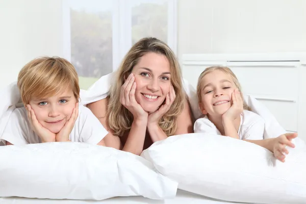 Madre e hijos acostados en la cama por la mañana — Foto de Stock