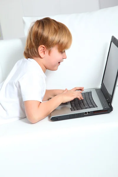 Menino usando computador portátil em casa — Fotografia de Stock
