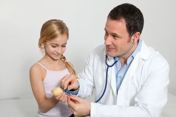 Médico y niña escuchando la respiración de la muñeca — Foto de Stock