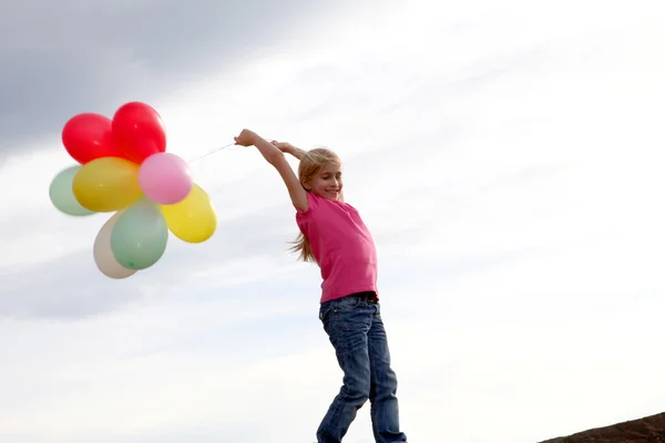 Девочка держит воздушные шары в сельской местности — стоковое фото