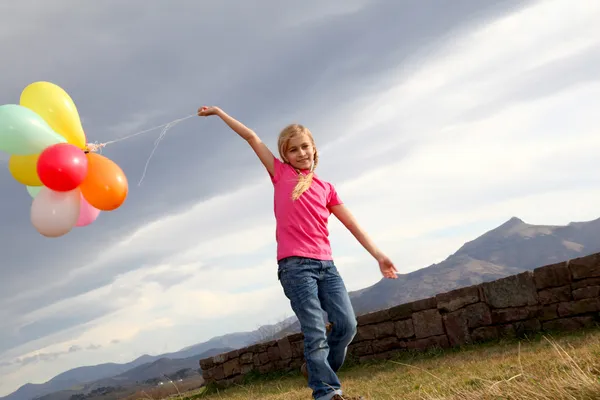 Liten flicka håller ballonger ut på landsbygden — Stockfoto