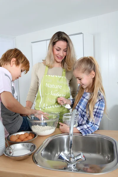 Moeder en kinderen in keuken bereiden cake — Stockfoto