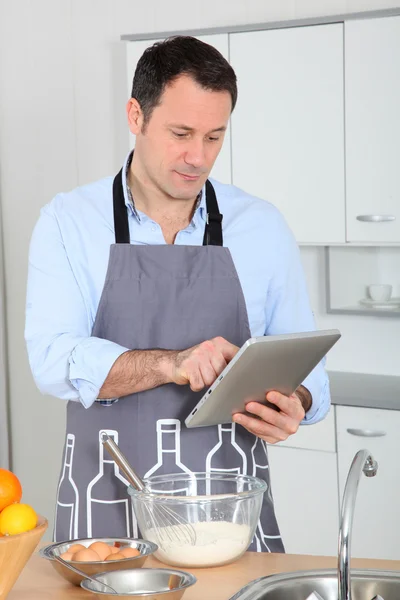 Человек смотрит на рецепт в Интернете — стоковое фото