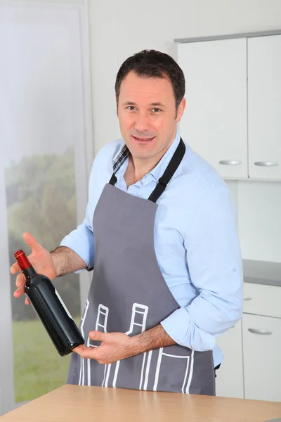 Un bel homme tenant une bouteille de vin rouge — Photo