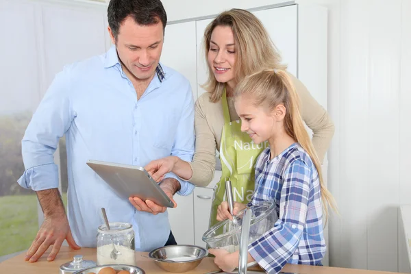 Parents and daughter preparing meal in home kitchen — Stock Photo, Image