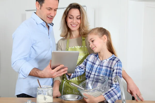 Parents and daughter preparing meal in home kitchen — Stock Photo, Image