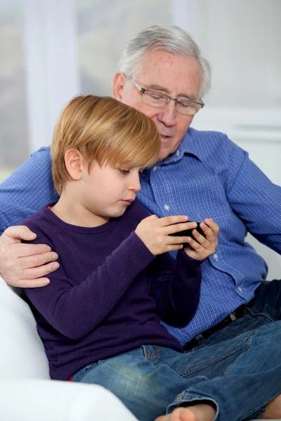 Oude man met kleine jongen videospel afspelen op telefoon — Stockfoto