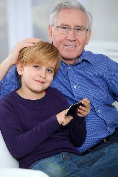 Old man with little boy playing video game on telephone — Stock Photo, Image