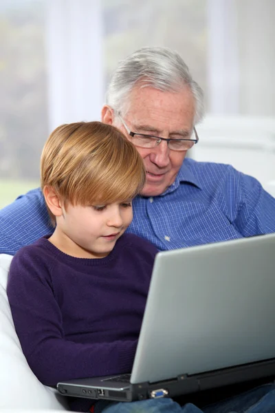 Літній чоловік з онуком за допомогою портативного комп'ютера — стокове фото