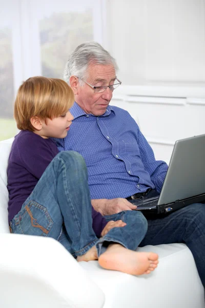 Anciano con nieto usando computadora portátil — Foto de Stock