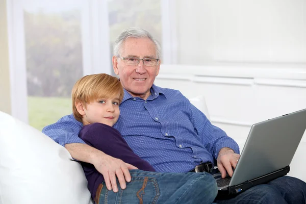 Älterer Mann mit Enkelkind nutzt Laptop — Stockfoto