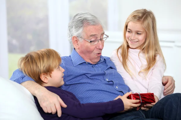 Kids giving birthday gift to their grandfather — Stock Photo, Image