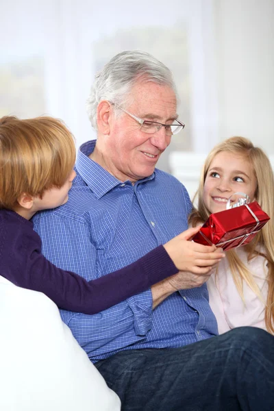 Niños dando regalo de cumpleaños a su abuelo — Foto de Stock