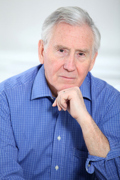 Портрет улыбающегося старика с рукой на подбородке
